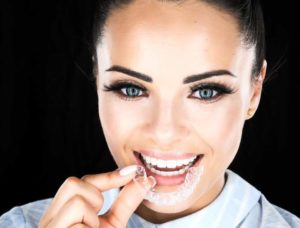 smiling girl with invisalign in hand